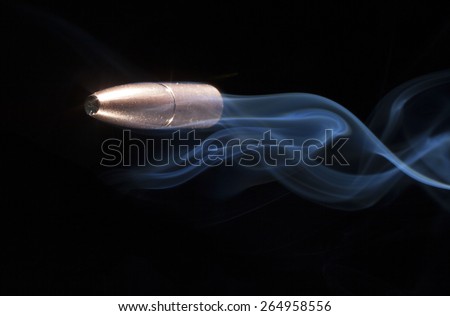 Copper plated bullets with blue smoke in tow on a black background
