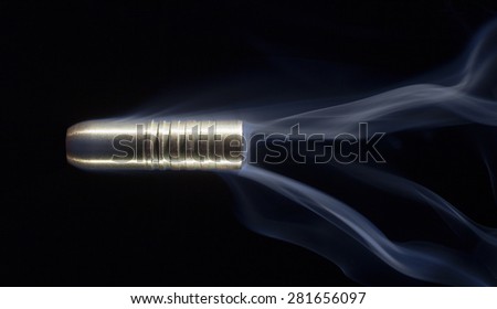 Big copper bullet with smoke trailing behind on a black background
