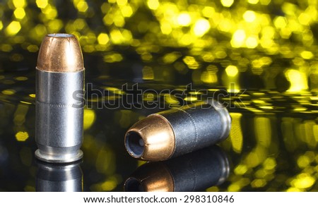 Two handgun cartridges with hollow point bullets and a yellow background