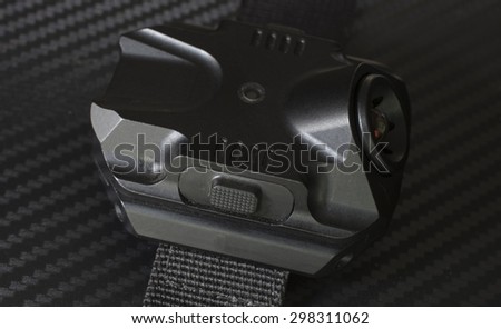 Side view of a tactical flashlight and activation button that is worn on the arm