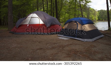Two tents that are pitched in a campsite next to a lake