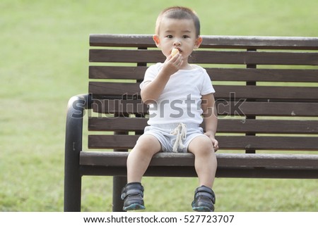 Cute Chinese baby boy eating bread in a park, shot in Beijing, China