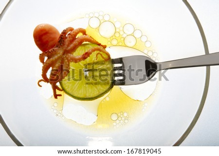 raw octopus ingredient isolated on fork white background lime slice top view