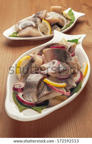 Seafood appetizer herring fish fillet with vegetables, white plates in the form of fish