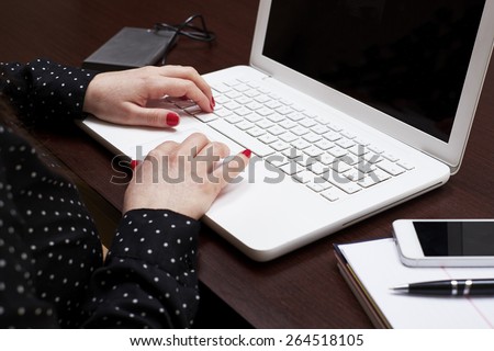 Woman hands typing on a laptop keyboard on a desk with a phone and a diary