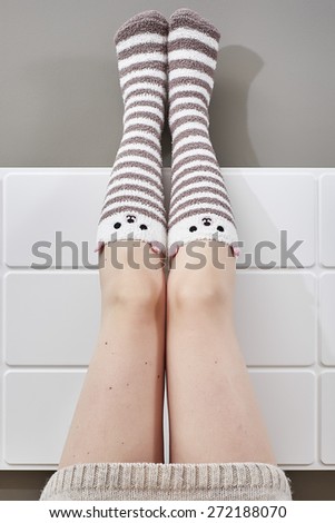 Woman legs raised up on bed wearing bear lined socks.