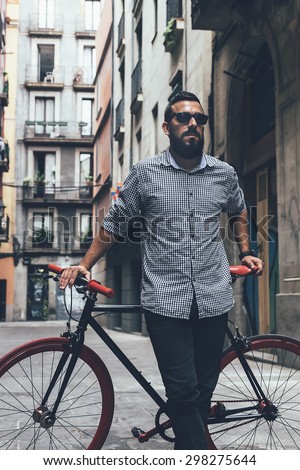 Cool Young bearded hipster besides a fixie bicycle on the street