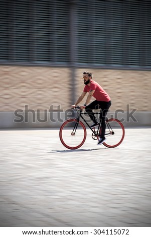 Young bearded man riding a Fixed Gear Bicycle on a Street