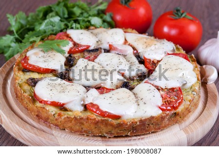 Zucchini pizza and cheese on a wooden board, close-up