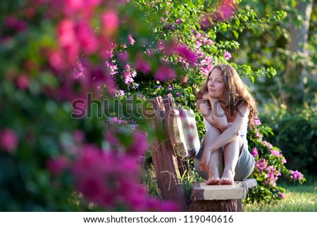 Woman sitting on the bench inside the flowers garden