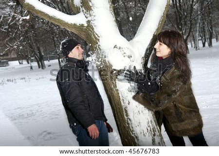 Young beautiful couple playing with snow in winter park. Girl throw some snow to her boyfriend