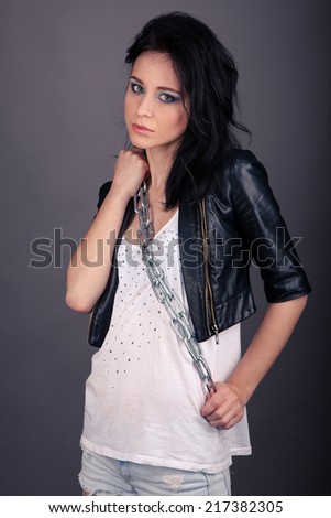 pretty girl in leather jacket with chains on his hands on a gray background