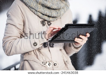 The girl on the tablet smartphone in winter park. Close-up in the hands of a tablet computer.