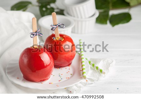 Apples in a red candy on sticks, candy apple on a wooden background