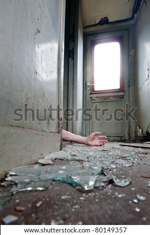A person lying in doorway unconscious in messy environment.