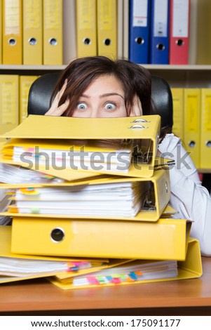 Young secretary distressed with a lot of documents on her desk