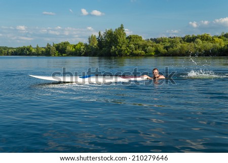 Young attractive man swiming with stand up paddle board in the lake, SUP