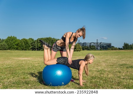 Pretty young caucasian woman couple training with balance ball in the park