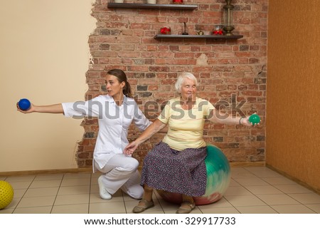 Senior Woman Sitting On A Gym Ball And Doing Exercises At Physiotherapy