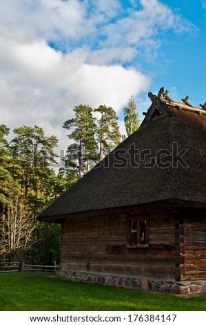 Old log cabin in the wooded forest of evergreen trees. Open-air ethnography museum near Riga, Latvia.