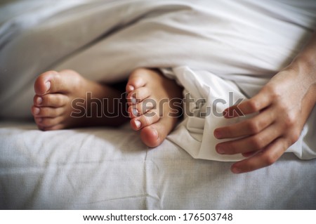Sleeping child feet and hand on white bed linen