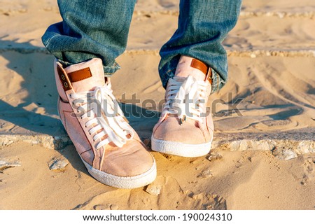 Teenage girl legs and feet in pink denim/jeans trendy modern shoes. Outdoors closeup.