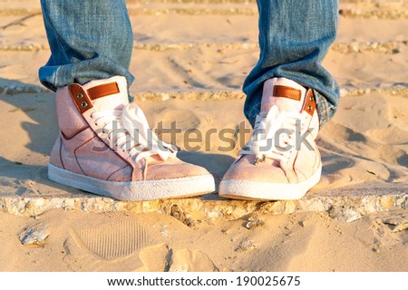 Teenage girl legs and feet in pink denim/jeans trendy modern shoes. Outdoors closeup.