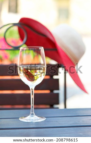 Glass of delicious white wine on wooden table in summer restaurant. Outdoors.