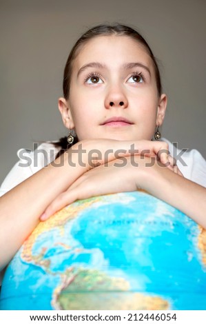 Back to school. Smiling thoughtful schoolgirl with blue round globe dreaming about the future. Childhood and education.
