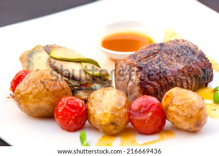 Prime grilled juicy beef steak with roasted vegetables. Outdoors close-up.
