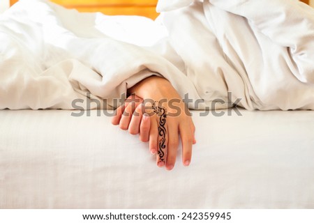 Sleeping little child hands with tattoo on white bed linen. Indoors closeup.