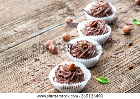 Row of homemade chocolate cupcakes with hazelnuts on top. Wooden background. Indoors still-life.