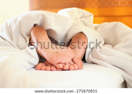 Sleeping little child funny dirty feet on white bed linen. Indoors closeup.