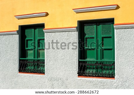 Two green windows with wooden shutters on multicolored wall. Canary Islands ,Tenerife. Spain.