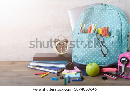 School backpack with coloured pencil and school supplies on brown wood table background. Back to school concept.