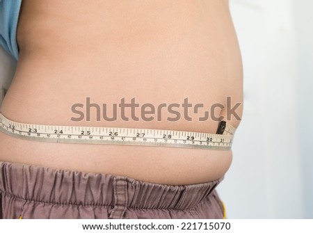 fat boy measuring him stomach focus on tape