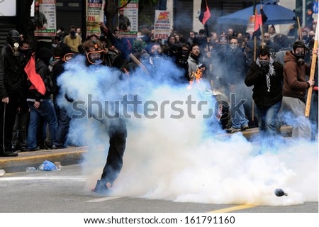 ATHENS, GREECE - FEBRUARY. 23: A young protester wearing a gas mask kicks a tear gas canister away from his group. Athens, February 23 , 2011.