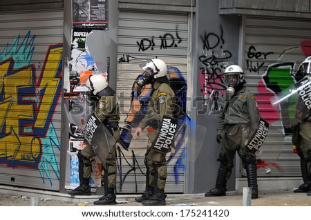 ATHENS, GREECE - DECEMBER 07. Riot police officers wearing a gas mask in front of graffiti of a gas mask, during clashes in Athens, December 07, 2008.