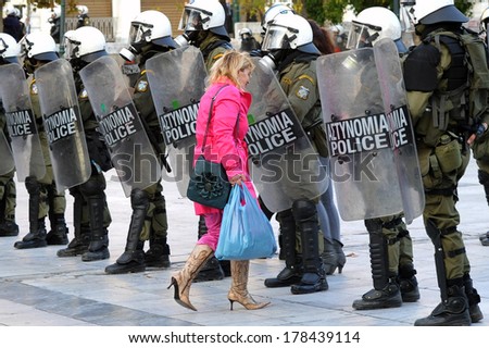ATHENS, NOV. 17. Greek economic crisis. During a day with a demonstration, a woman carrying shopping bags goes through the riot police line in Athens, Syntagma  square, November 17, 2014