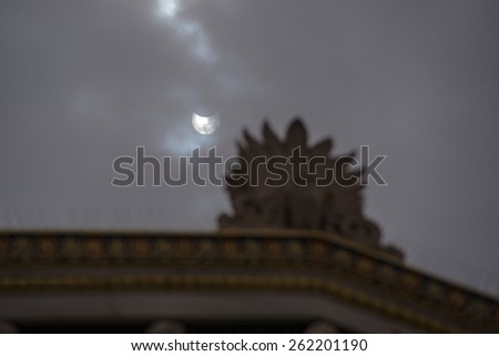 Athens Greece, March 20, 2015. The partial solar eclipse as seen in partly cloudy sky above the roof of the Academy of Athens, local time 11:53.