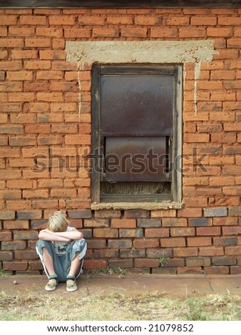 Young boy behind old house