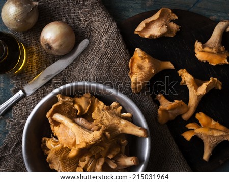Mushrooms in aluminium dish on the blue table with onions and a knife