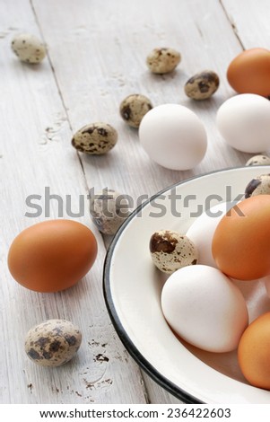 Chicken and quail eggs on the white wooden table vertical