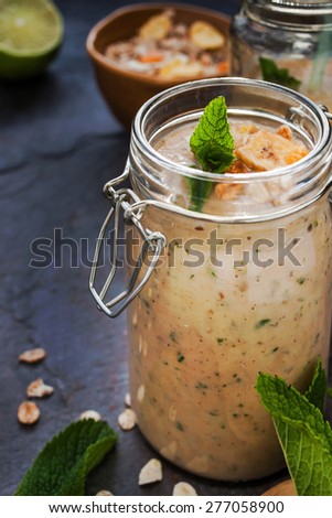 Fruit smoothie in a glass jars with mint on the blue stone table