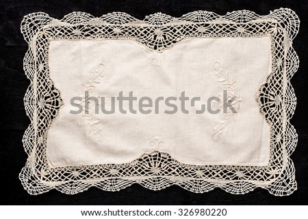 Old vintage napkin with lace border on the black wooden table