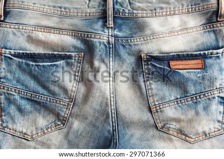 Close-up of a plain back pocket of a pair of well-worn and tattered jeans.