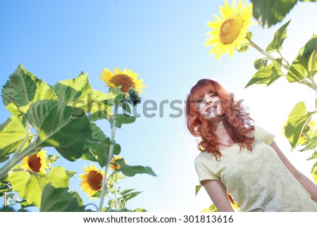 Beautiful red-haired girl in sunflowers