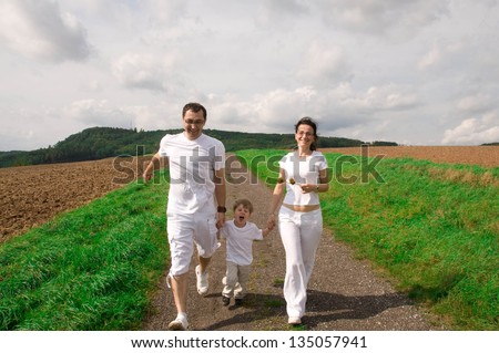 Mother, father and child run down the road.