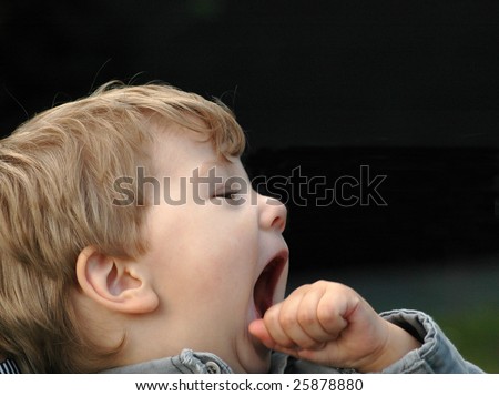 A child yawns. He is tired and wants to sleep.