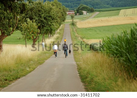 Cyclists and dog are walking on a road